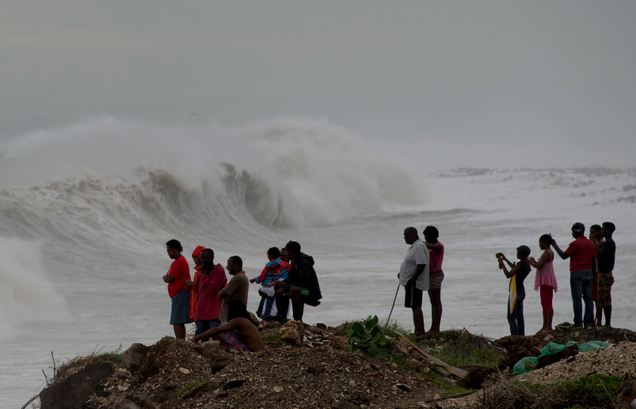 People stand watching the surf on the outskirts of Kingston, Jamaica on October 3rd. Image: AP